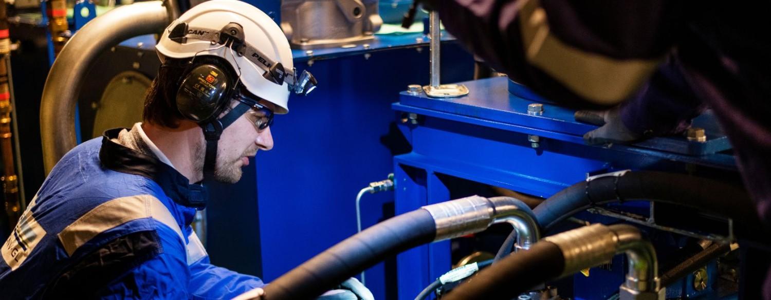 Engenheiros ajustando máquinas usando equipamentos de proteção individual (EPIs).