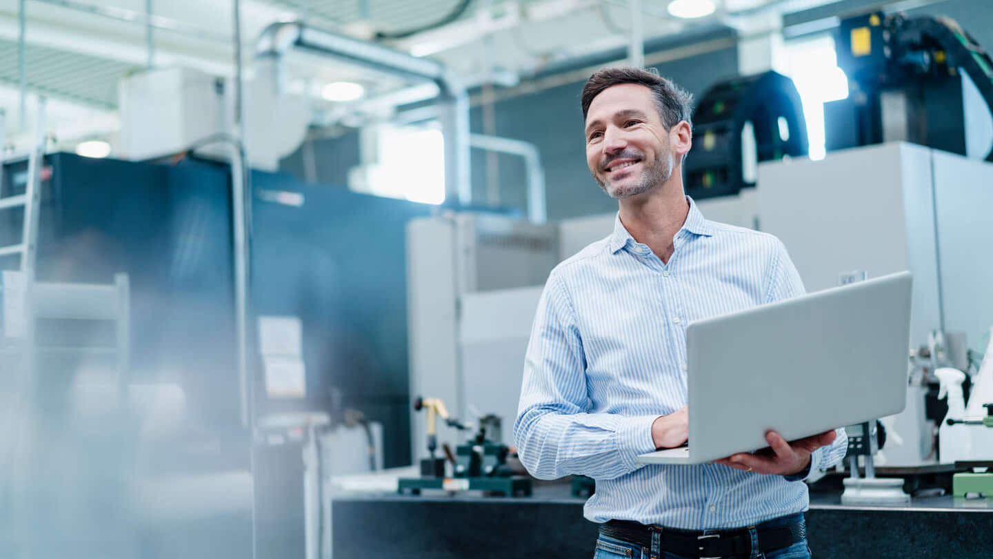 empresário segurando um laptop enquanto trabalha na indústria