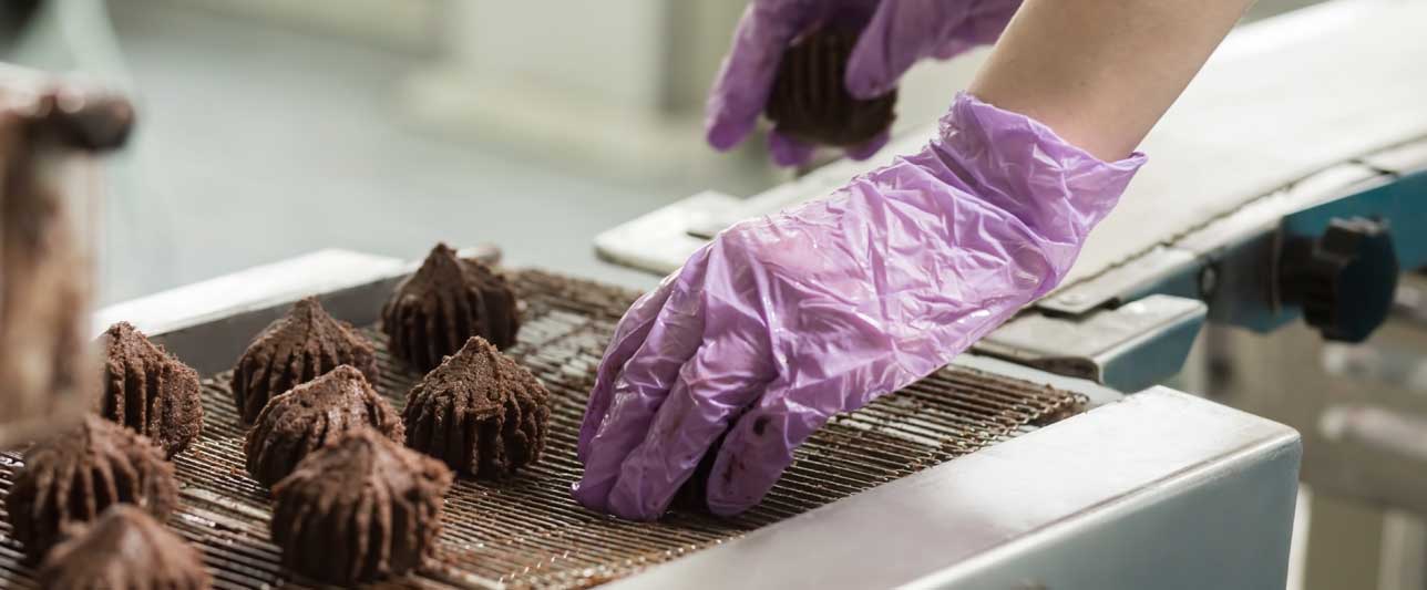 Hand putting sweets on conveyor